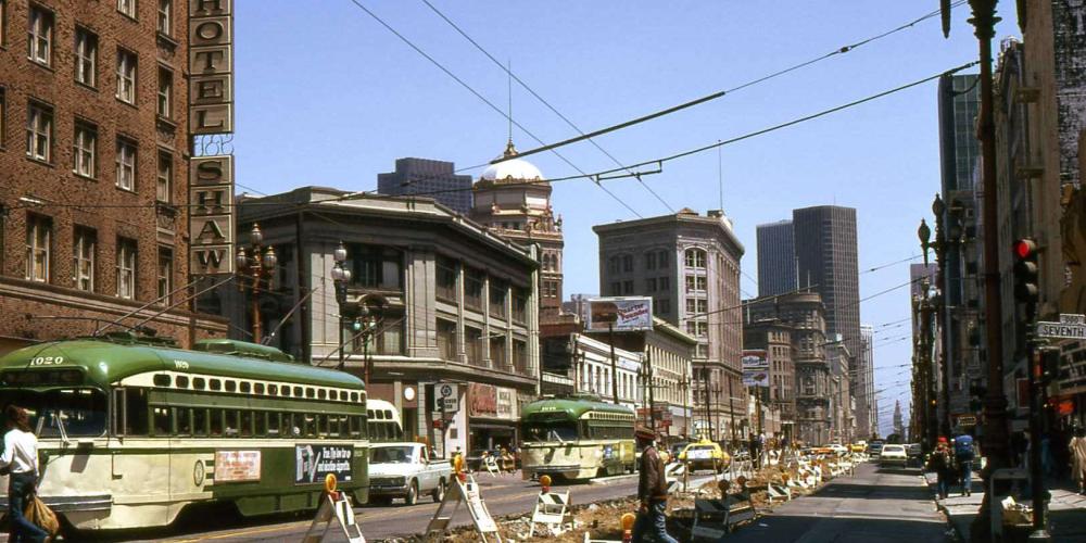 A vintage color photo from 1973 shows Seventh Street with a green trolley car on the left, construction in the road, and 2 pedestrians.