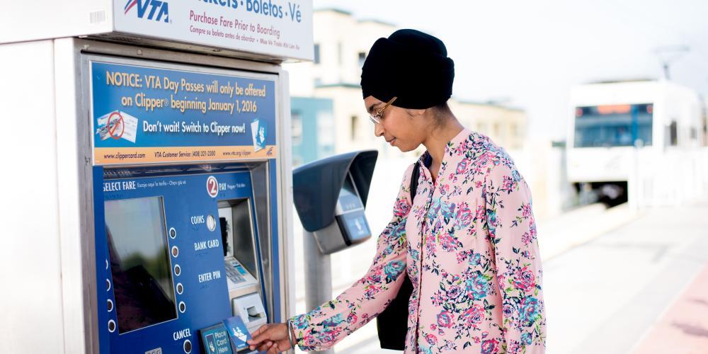 A woman uses a Clipper card at a VTA ticket machine.