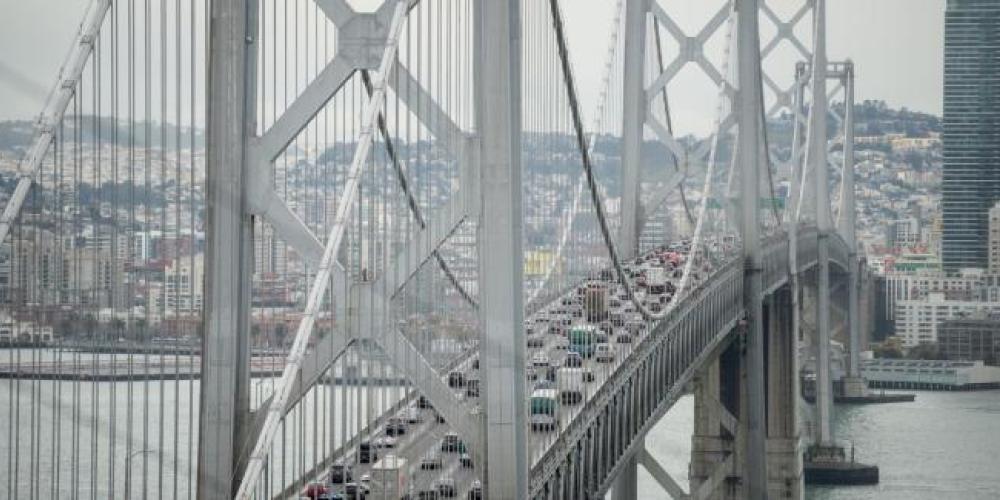 Cars travel west toward San Francisco on the upper deck of the Bay Bridge while SF's cityscape is in the background