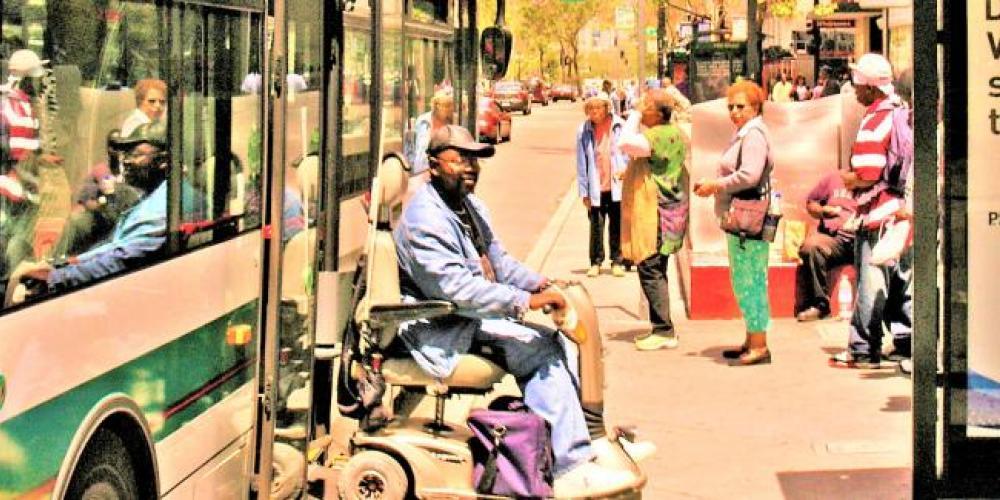 man in wheeled device getting off the bus