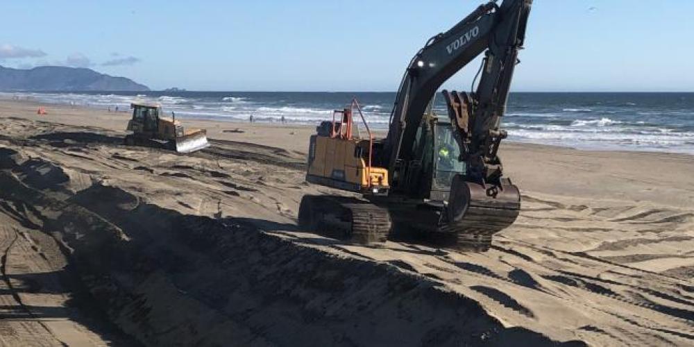 construction equipment moving sand on ocean beach