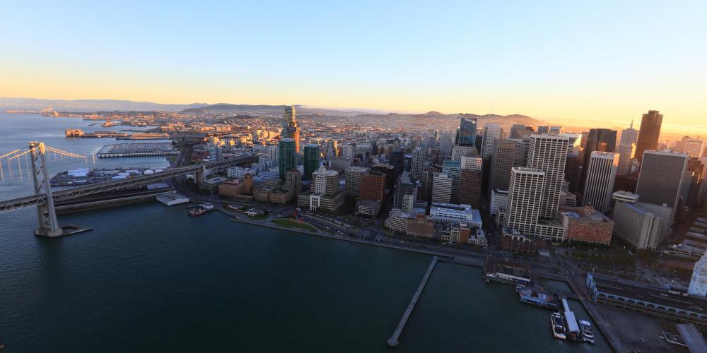 An aerial view of San Francisco's skyline between the Bay Bridge and the Ferry Building.